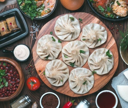 Gürcistan mutfağı, Kafkasya’nın tarihi ve kültürel zenginliğini sofralarına yansıtan köklü bir gastronomi geleneğine sahiptir. Yüzyıllardır farklı medeniyetlerin etkisiyle şekillenen bu mutfak, hem Doğu hem de Batı lezzetlerini bir araya getirir. Ülkenin farklı bölgelerinde yetişen sebze, meyve, tahıl ve et ürünleri, mutfak kültürünün çeşitlenmesini sağlamıştır. Gürcüler için yemek, yalnızca karın doyurmak değil, aynı zamanda kültürel bir paylaşım ve misafirperverlik göstergesidir. Konulu bir haber görseli.