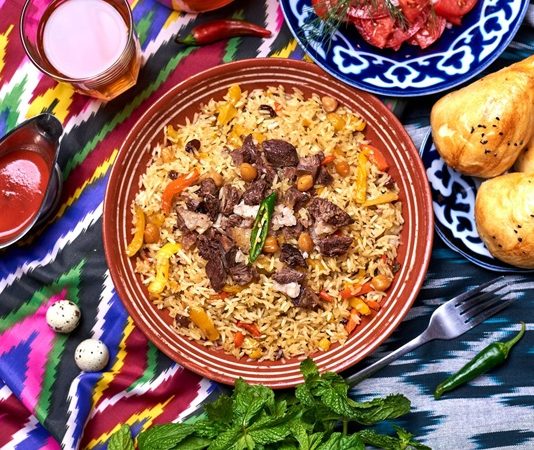 Özbekistan Mutfağı Özbekistan mutfağı, Orta Asya’nın bereketli topraklarında, tarih boyunca farklı kültürlerin etkisiyle şekillenmiş zengin bir gastronomi mirasına sahiptir. İpek Yolu’nun kesişim noktalarından biri olan Özbekistan, hem Doğu hem de Batı mutfak geleneklerini harmanlamış, yemek kültürünü çeşitlendirmiştir. Et ve tahıllar, mutfağın temelini oluştururken; baharatlar ve taze sebzeler, yemeklere özgün tat ve aroma kazandırır. Konulu bir haber görseli.