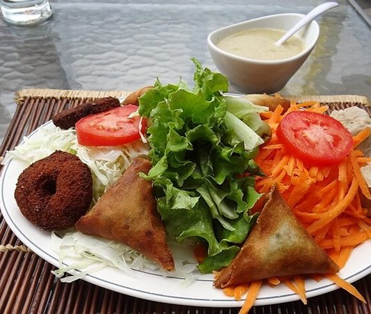 Reunion Mutfağı, Hint Okyanusu’nda yer alan Reunion Adası’nın zengin kültürel mirasını sofralara taşır. Ada mutfağı, Fransız, Afrika, Hint ve Çin etkilerini bir araya getirerek kendine özgü bir tat profili oluşturur. Bu kültürel çeşitlilik, yemeklerde hem renk hem de aromatik derinlik sağlar. Konulu bir haber görseli.
