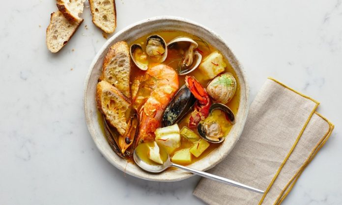 Fransa’nın güney sahillerinde doğan Bouillabaisse, yüzyıllardır Akdeniz mutfak kültürünün en önemli simgelerinden biri olarak biliniyor. Marsilya balıkçıları tarafından geliştirilen bu özel yemek, hem köklü tarihi hem de aromatik yapısıyla son yıllarda yeniden uluslararası arenada büyük bir popülerlik kazandı. Özellikle gastronomi dünyasında artan özgün tarif arayışı, Bouillabaisse gibi geleneksel lezzetleri yeniden öne çıkarıyor. Akdeniz’in karakteristik dokusunu yansıtan çorba, içerdiği taze balıklar, kabuklular ve aromatik sebzelerle hem besleyici hem de kültürel bir değer taşıyor. Konulu bir haber görseli.