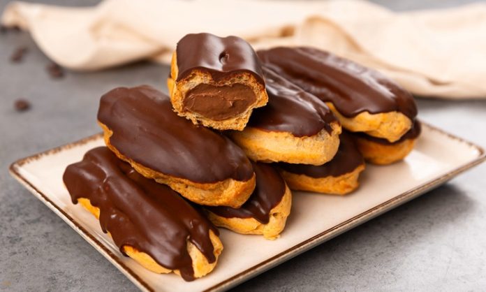 Eclair’in Tatlı Dünyasına Yolculuk Fransa’dan Dünyaya Uzanan Eşsiz Bir Lezzet Fransız pastacılığının dünya mutfağına kazandırdığı en özel tatlardan biri olan eclair, yalnızca görünümüyle değil, ince dokusu ve hafif dolgusu ile de tatlı severlerin vazgeçilmezi olarak gösteriliyor. Günümüzde pek çok pastane menüsünde rastladığımız bu tatlı, aslında aristokrat mutfaklarından çıkıp modern mutfaklara taşınan çok katmanlı bir tarihe sahip. Özellikle çikolata kaplaması ve iç dolgusu ile bilinen eclair, Avrupa’da uzun yıllardır tüketilen bir tatlı olmakla birlikte, son yıllarda Türkiye’de de giderek daha fazla tercih edilmeye başladı. Pastacılığın gelişimi ile beraber farklı dolgular, farklı çikolata türleri ve daha çeşitli glazürlerle sunulan bu tatlı, gastronomik açıdan ciddi bir çeşitliliğin de öncüsü haline geldi. Konulu bir haber görseli.