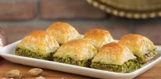 Türkiye’nin en özel tatlılarından biri olan baklava, yüzyıllar boyunca hem coğrafyalara hem de kültürlere yayılan zengin bir mirasa sahip. Orta Asya’dan Anadolu’ya uzanan serüveniyle bugün dünyanın dört bir yanında tanınan bir lezzet hâline gelen baklava, Osmanlı mutfağından itibaren saray sofralarının vazgeçilmez tatlısı olarak kayıt altına alınmıştır. Bu süreçte tatlının yapım teknikleri geliştirilmiş, farklı yörelerde kendine has çeşitleri ortaya çıkmıştır. Gaziantep baklavası, bu tarihsel yolculukta en çok bilinen ve coğrafi işaret tesciline sahip örneklerden biridir. Konulu bir haber görseli.