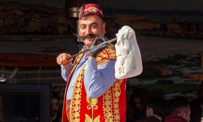 Gelenekten Lezzete Maraş Dondurmasının Hikâyesi ve Günümüzdeki Yeri Türkiye’nin gastronomi mirası içinde kendine özgü yapısı, üretim tekniği ve kültürel arka planıyla öne çıkan Maraş dondurması, yalnızca bir tatlı değil aynı zamanda köklü bir geleneğin günümüze taşınmış hâli olarak kabul ediliyor. Özellikle yaz aylarında yoğun ilgi gören bu eşsiz lezzet, dayanıklı yapısı, bıçakla kesilebilen kıvamı ve kendine has aromasıyla klasik dondurmalardan ayrılıyor. Kahramanmaraş ile özdeşleşen bu ürün, bugün hem yerel ekonominin hem de Türkiye’nin tanıtım yüzlerinden biri hâline gelmiş durumda. Konulu bir haber görseli.