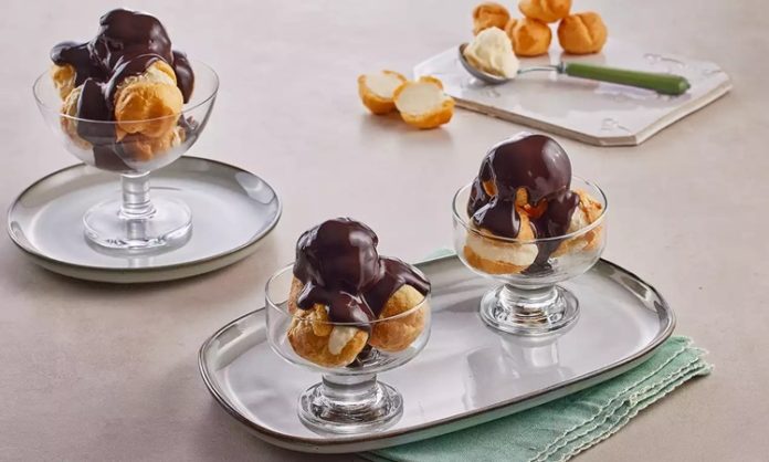 Fransız mutfağının en seçkin tatlılarından biri olan profiterol, uzun yıllardır hem restoranların hem de ev mutfaklarının en sevilen lezzetlerinden biri olarak yerini koruyor. Çıtır hamurun içindeki hafif krema ve üzerine dökülen yoğun çikolata sosuyla oldukça cezbedici bir tat sunan profiterol, özellikle misafir ağırlamalarında şık bir sunum oluşturmasıyla ön plana çıkıyor. Günümüzde pastane vitrinlerinde sıkça görülen bu tatlı, son dönemde ev yapımı tariflerin popülerleşmesiyle birlikte mutfakta daha da yaygın şekilde hazırlanıyor. Konulu bir haber görseli.
